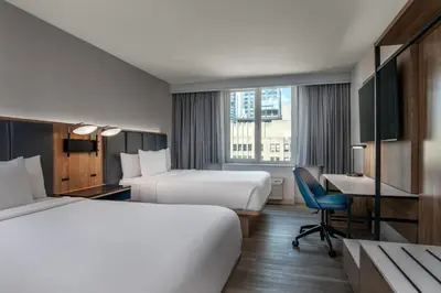 a hotel room with two beds and a desk at Courtyard by Marriott Times Square West in New York
