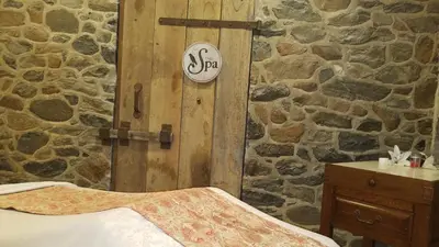 a bedroom with a stone wall with a bed and a wooden door at The Inn at Montchanin Village & Spa in Montchanin
