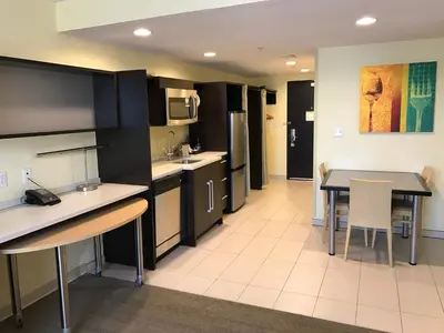 a kitchen with black cabinets and a table and chairs at Home2 Suites by Hilton Rahway in Rahway