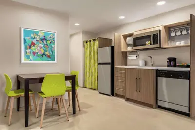 a kitchen with a table and green chairs in a room at Home2 Suites By Hilton Glen Mills Chadds Ford in Glen Mills