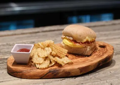 a sandwich and chips on a wooden board with a dipping sauce at Best Western Premier Herald Square in New York