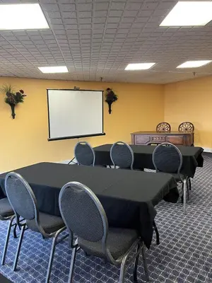 a conference room with a table and chairs and a white screen at Appalachian Hotel in Carlisle