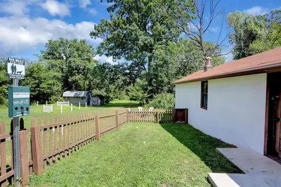 a fence next to a white building with a yard at Stay On State - 15 Min to Harrisburg, 30 Min to Carlisle 2BR tastefully decorated in Duncannon