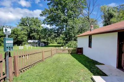 a fence next to a white building with a yard at Stay On State - 15 Min to Harrisburg, 30 Min to Carlisle 2BR tastefully decorated in Duncannon