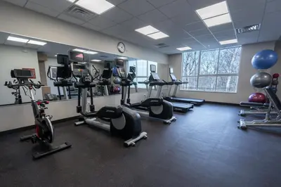 a gym with several tread machines and a clock at TownePlace Suites by Marriott Clinton in Clinton