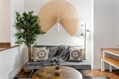 a living room with a gray couch and a large fan at Sleeps 4! 2BR, Gym, Paid Parking, Close to Major Attractions in Philadelphia