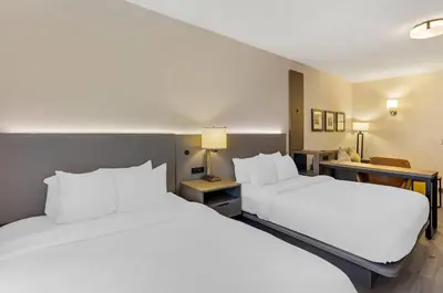 two beds in a hotel room with white pillows at Comfort Inn & Suites Sayre in Sayre