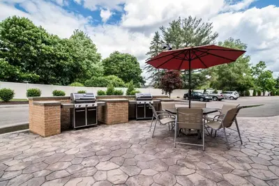 a patio with an outdoor kitchen and an umbrella at Comfort Inn & Suites Sayre in Sayre