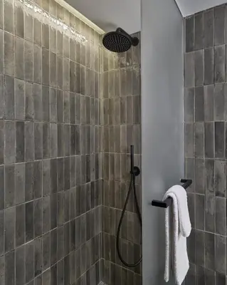 a bathroom with a shower with gray tiles at Hotel AKA NoMad in New York