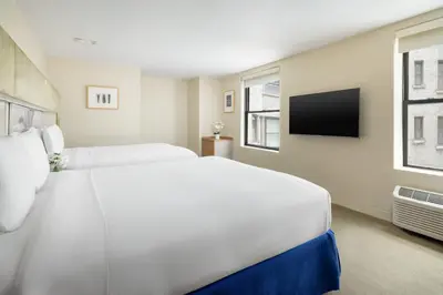 a white bedroom with a large bed and a tv at The Shoreham in New York