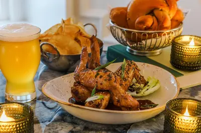 a plate of food on a table with a glass of beer at The Algonquin Hotel Times Square, Autograph Collection in New York
