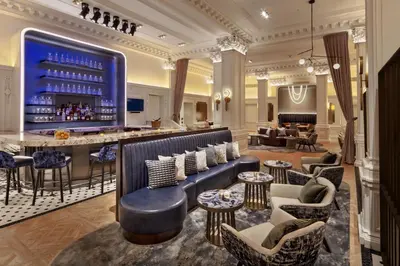 a hotel lobby with a bar with chairs and tables at The Algonquin Hotel Times Square, Autograph Collection in New York