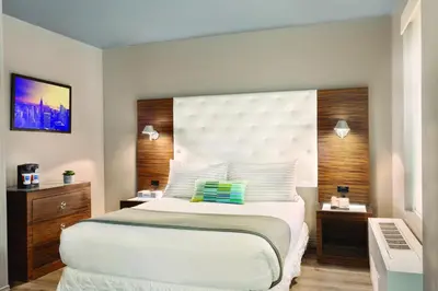 a bedroom with a large white bed and a desk at The Gallivant Times Square in New York