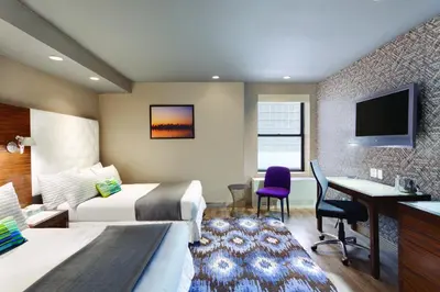 a hotel room with two beds and a desk at The Gallivant Times Square in New York