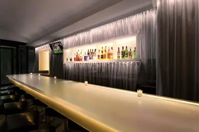 a bar with a long counter with bottles on the wall at The Gallivant Times Square in New York