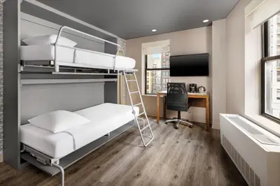 a bunk bed in a room with a desk and a chair at The Gallivant Times Square in New York