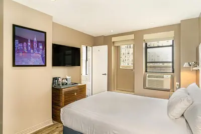 a bedroom with a bed and a flat screen tv at The Gallivant Times Square in New York