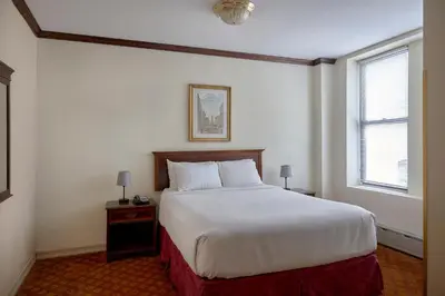 a bedroom with a large white bed and two windows at Night Hotel Broadway in New York