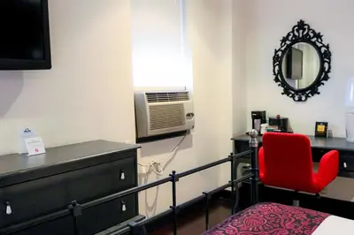 a bedroom with a bed and a red chair and a mirror at Night Hotel Broadway in New York