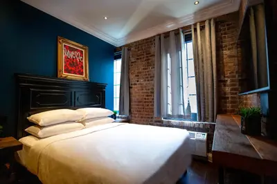 a bedroom with a large bed with blue walls and windows at Sohotel in New York