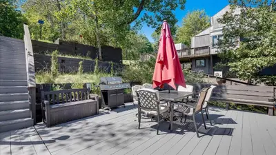 a patio with a table with a red umbrella and a grill at Cozy Modern Camelback House in Tannersville