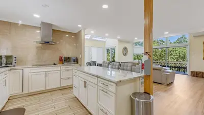 a large kitchen with white cabinets and a living room at Cozy Modern Camelback House in Tannersville