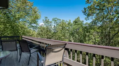 a deck with chairs and a table and trees at Cozy Modern Camelback House in Tannersville