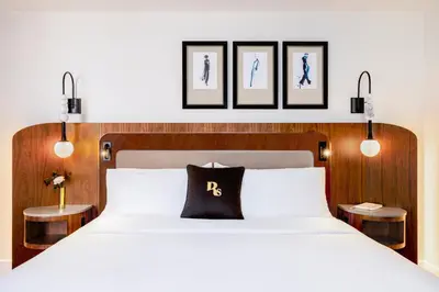 a bedroom with a white bed with three pictures on the wall at The Benjamin Royal Sonesta New York in New York