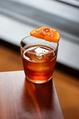 a drink with a orange slice on top of it at The Shelburne Sonesta New York in New York