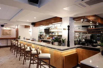 a bar with a row of chairs in a restaurant at The Shelburne Sonesta New York in New York