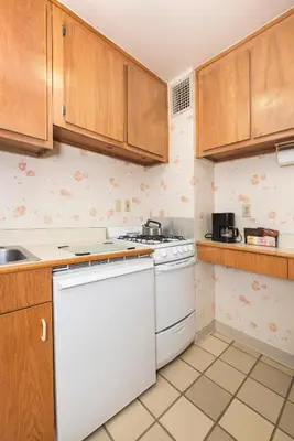 a kitchen with wooden cabinets and a white dishwasher at Murray Hill East Suites - Extended Stay in New York
