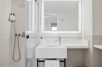 a white bathroom with a sink and a mirror at Newly Renovated Rooms at Club Quarters Hotel Times Square, New York in New York