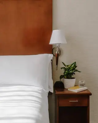 a bed with a white pillow and a lamp on a table at Club Quarters Hotel Rittenhouse Square, Philadelphia in Philadelphia