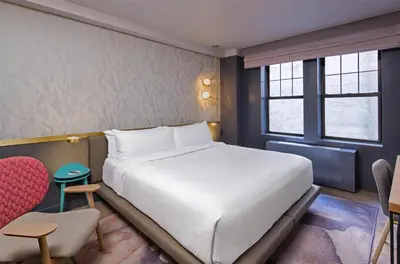 a bedroom with a white bed and a red chair at The Time New York, part of JdV by Hyatt in New York