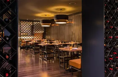 a dining room with tables and chairs and wine bottles at The Time New York, part of JdV by Hyatt in New York