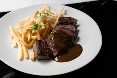 a plate of steak and french fries on a table at Hotel Belleclaire Central Park in New York