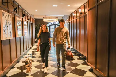 a man and woman walking down a hallway with their dogs at Hotel Belleclaire Central Park in New York