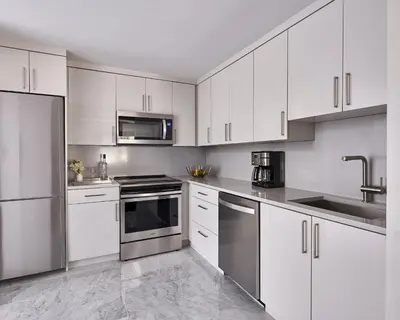 a kitchen with white cabinets and stainless steel appliances at AKA Central Park in New York