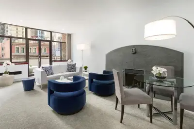 a living room with a glass table and blue chairs at Royalton New York in New York
