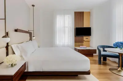 a white bedroom with a bed and a tv at Bryant Park Hotel in New York