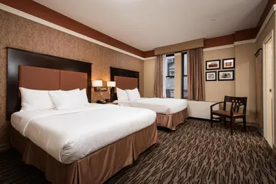 a hotel room with two beds and a chair at The Hotel at Fifth Avenue in New York
