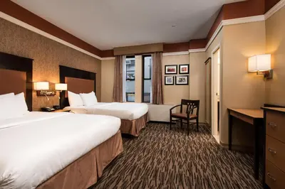 a hotel room with two beds and a desk at The Hotel at Fifth Avenue in New York