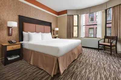 a hotel room with a large bed and a chair at The Hotel at Fifth Avenue in New York