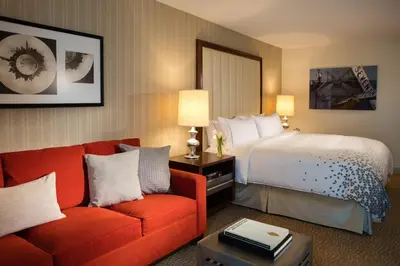 a hotel room with a bed and a red couch at Renaissance Newark Airport Hotel in Elizabeth