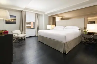 a bedroom with a large white bed and a desk at The Michelangelo New York in New York
