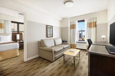 a hotel room with a couch and a bed and a desk at New Yorker by Lotte Hotels in New York