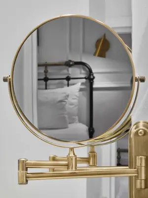 a round gold mirror on a brass shelf with a bed at Life Hotel New York in New York