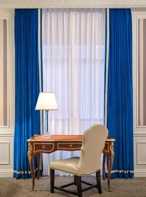 a desk with a chair next to a window with blue curtains at 5th & 55th Residence Club in New York