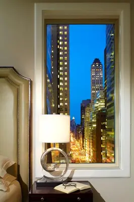 a bedroom with a window with a view of a city at Omni Berkshire Place in New York