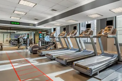 a gym with rows of treadmills and machines at Omni Berkshire Place in New York
